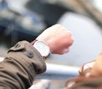 A person checks their wristwatch in a hurried outdoor setting, emphasizing time management.